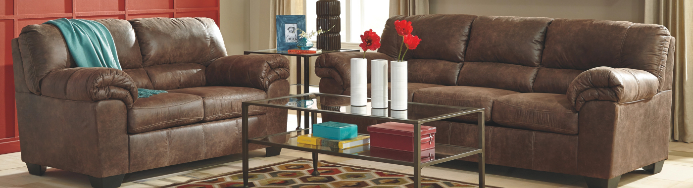 two brown leather couches around a glass coffee table with a vase of bright red poppies